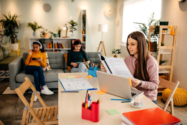 istock Mother finishes work on a laptop while her daughters play on the bed behind her 1313539396