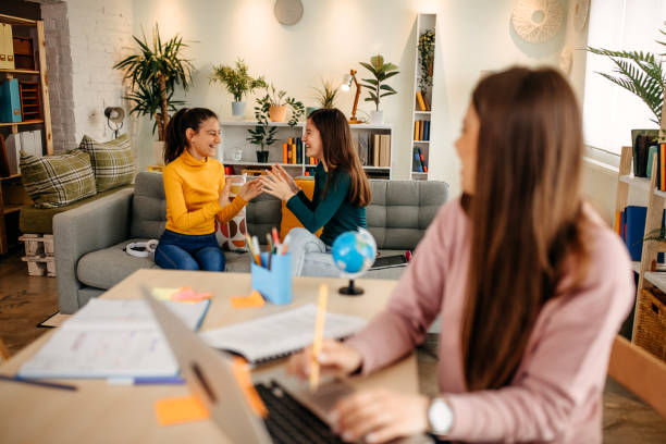 istock Mother finishes work on a laptop while her daughters play on the bed behind her 1313540696
