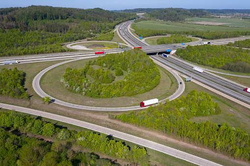 Aerial view of curvy highway junctions with cars and trucks in spring/summer.