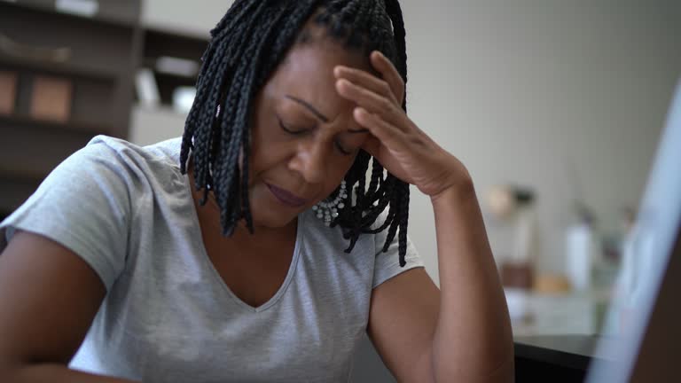 Worried mature woman with headache working at home