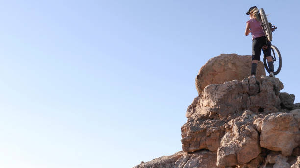 She carries bike up to top of the mountain, and looks out
