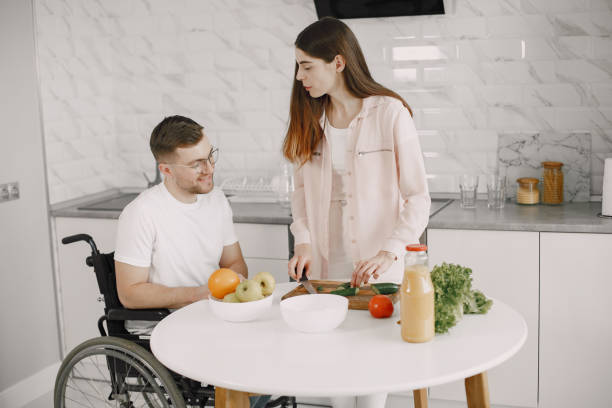 istock Wife encourage disabled husband sitting in wheelchair at kitchen table 1313548603