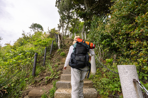 Japanese female friends hiking in Kamakura to enjoy walking in nature covered with fresh green leaves and viewing the scenery from the top.