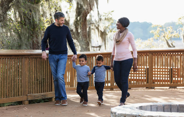 istock Interracial family with twin boys walking in park 1313552949