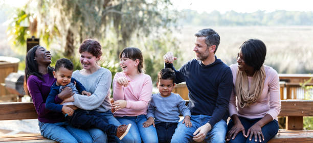 familia mezclada con cinco niños sentados en el banco del parque - child group of people teenager sibling fotografías e imágenes de stock