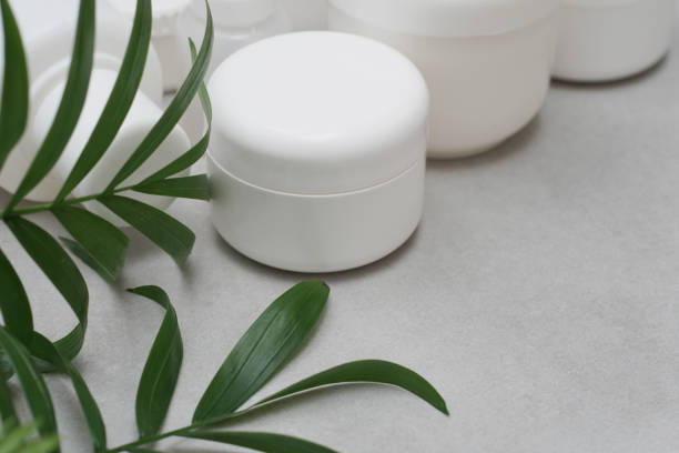Mock-up.
Empty jars for cosmetic cream.
White plastic containers for skincare products without labels.
Unbranded beauty product package.
Decorated with green leaves.
Cosmetic or pharmacy concept. stock photo