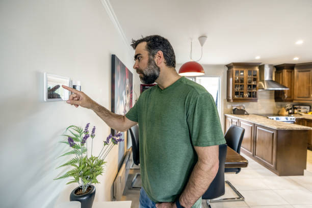 istock Man Using Home Automation on Digital Tablet to Open Lights in Kitchen and dining room 1313554148