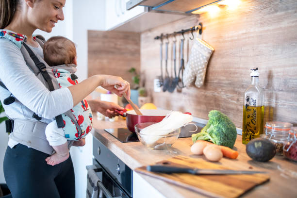 istock Multi-tasking mother preparing meal while carrying her baby 1313556020