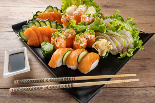 mezcla de sushi y niguiris en plato negro sobre mesa de madera - niguiri sushi fotografías e imágenes de stock