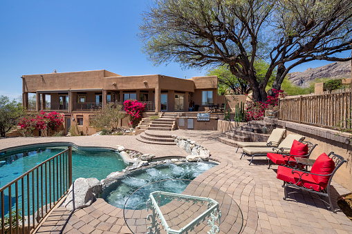 Swimming pool with hot tub and terraced patio at a luxury home in a desert environment.