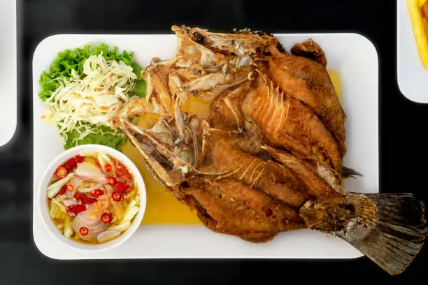 Photo of Fried Sea bass with fish sauce and spicy mango sauce in Thai restaurant.