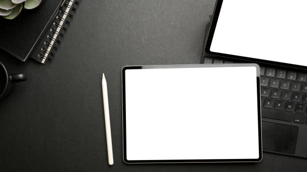 istock Top view of dark workspace with two tablets, accessories, stationery and copy space 1313574058
