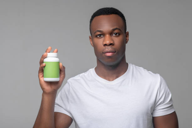 istock Dark skinned man holding medicine in hand 1313574888