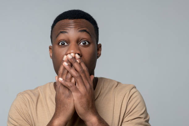 istock Shocked dark skinned man touching palms to mouth 1313574930