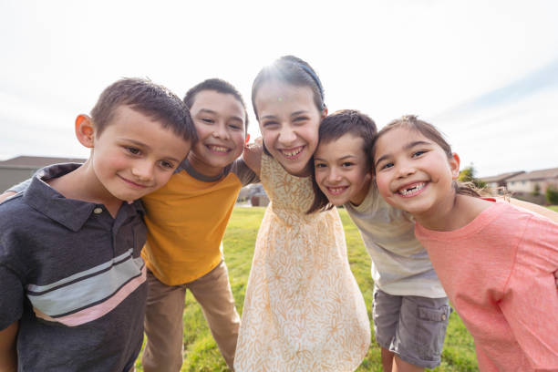 istock Mixed race group of elementary age friends embracing while playing outdoors 1313575073