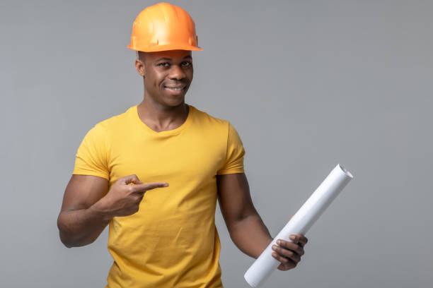 istock Man in helmet pointing with finger at paper scroll 1313575158