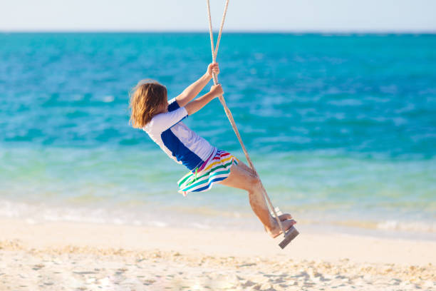 istock Child on swing. Kid swinging on beach. 1313577080