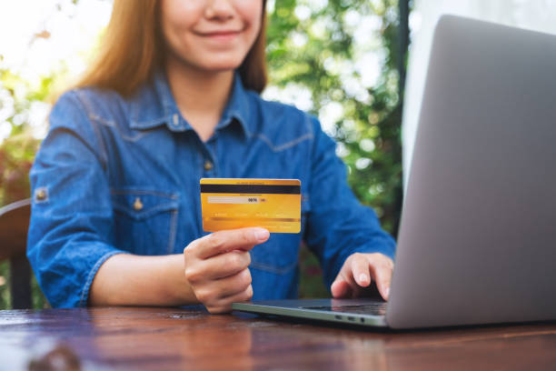 istock a woman holding credit cards while using laptop computer for online shopping 1313580309