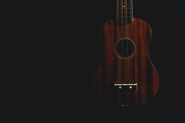 ukulele in legno marrone isolato su sfondo nero - uke foto e immagini stock