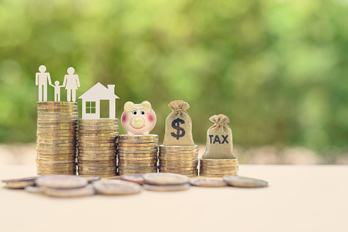 Family couple, home model, piggy bank, dollar and tax bags on stacks of rising coins