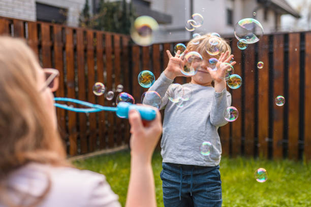 istock Caucasian Mother Blowing Bubbles with Her Son in Backyard 1313585150