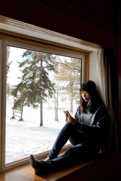 On phone - mature woman with mobile at window