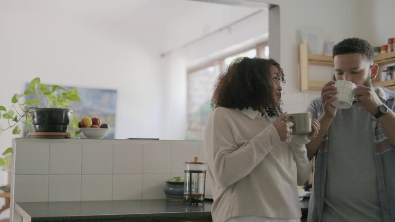 4k video footage of a young couple drinking coffee together in the kitchen at home