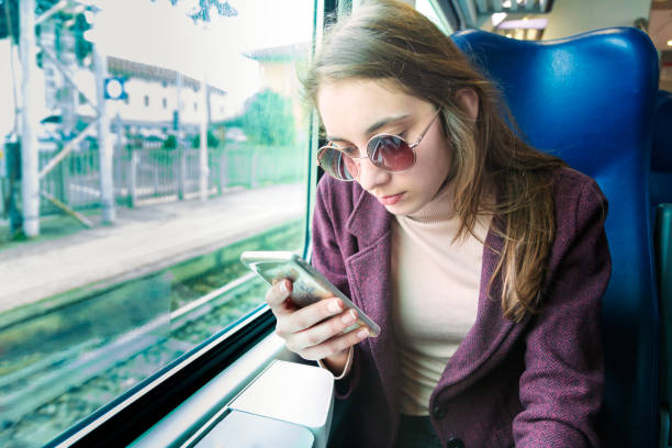 istock Young girl using smart phone in subway train 1313587246