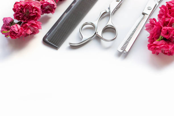 Professional scissors, comb and flower on a white background with copy space.