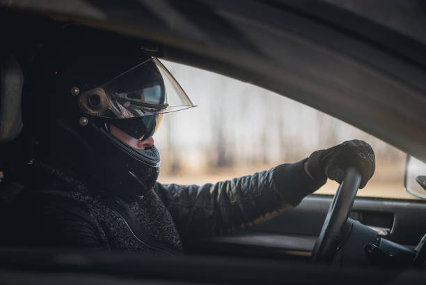 Rally racer concept. Rally driver concept. Man in a helmet is sitting by the car steering wheel close up. race car driver stock pictures, royalty-free photos & images