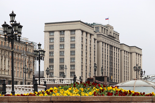 View through flowers to facade of State Duma of Russia with flag