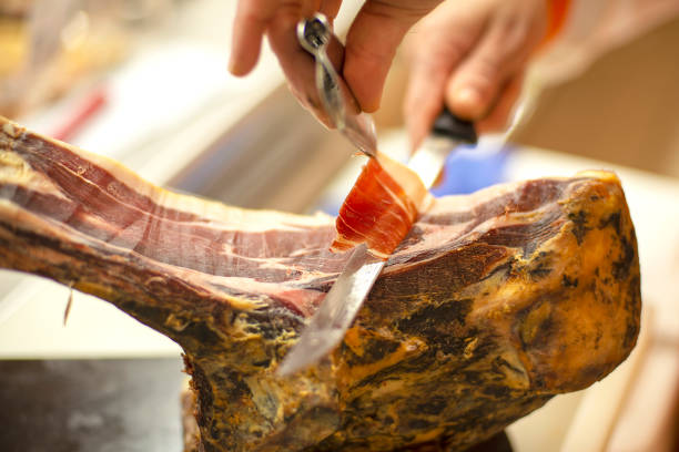 istock Close-up on person's hands slicing delicious cured cured ham carving 1313593756