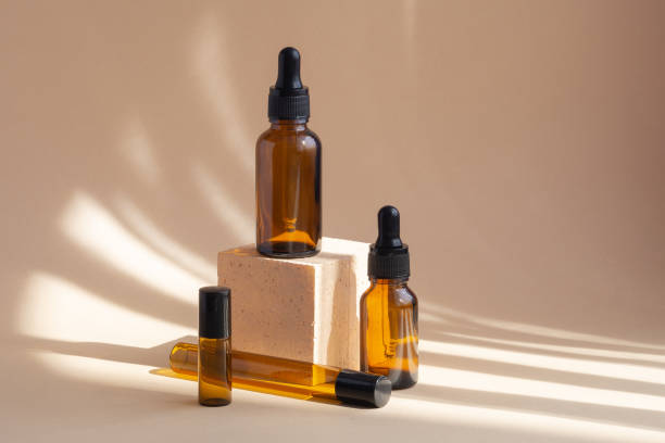 istock Four brown glass bottles, different shapes, on beige background with shadows from the sunlight. 3d square podium, for presentations. Concept of skin care. Natural cosmetics 1313595130