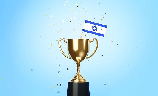 Star shaped gold confetti falling onto a gold cup in which a tiny Israeli flag sitting before blue background. Horizontal composition with copy space. Front view. Championship concept.