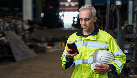 The chief engineer is using his phone and drinking coffee during the break. Lazy workers stop working and play on their phones, chats or social media. During work time at factory in worker concept