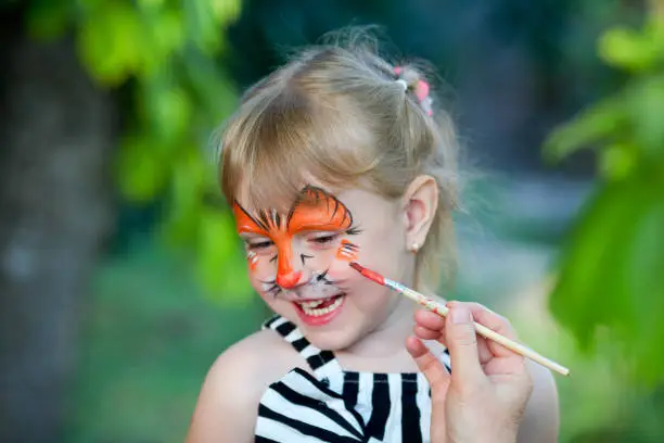 Adorable girl getting her face painted