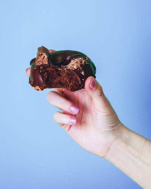 istock Chocolate doughnut in hand on blue background. 1313607214