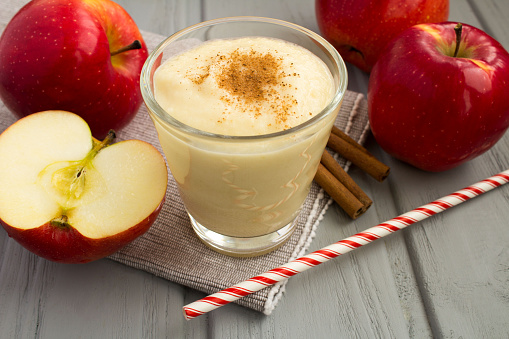 Smoothie from red apples and cinnamon on the gray background. Close-up.