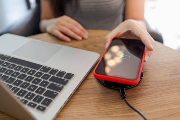 istock Charging mobile phone battery with wireless device in the table. Smartphone charging on a charging pad. Mobile phone near wireless charger. 1313608772