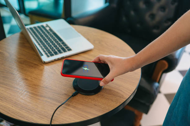 istock Charging mobile phone battery with wireless device in the table. Smartphone charging on a charging pad. Mobile phone near wireless charger. 1313608776