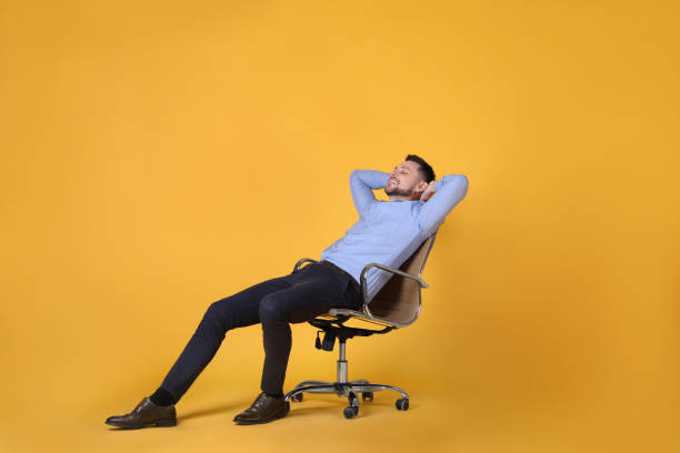 istock Handsome man relaxing in office chair on yellow background 1313615812