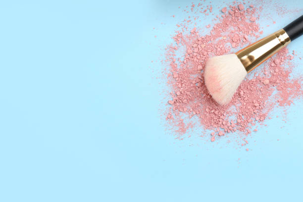 istock Makeup brush and scattered blush on light blue background, top view. Space for text 1313616152