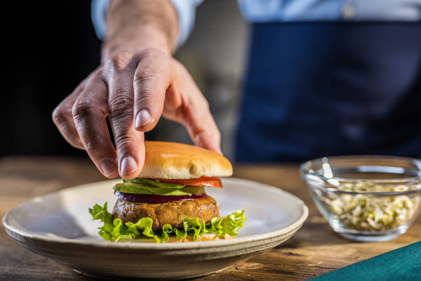 istock Male hand adding bread slice to vegan burger 1313617091