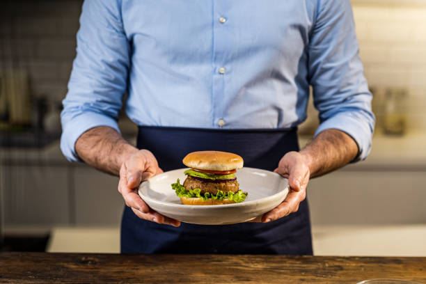 istock Man holding vegan burger served on plate 1313617093