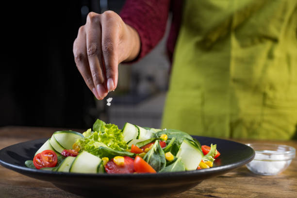 istock Woman's hand adding salt to salad 1313617158