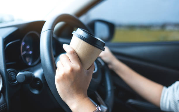 istock a woman holding and drinking coffee while driving a car 1313617318