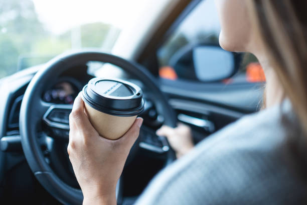 istock a woman holding and drinking coffee while driving a car 1313617494
