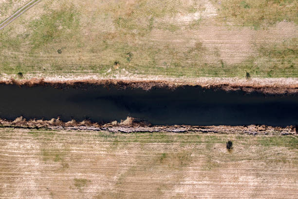 A small river, a sand ditch between the fields and the thickets seen from above, a photo from a drone.