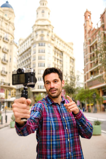 man records a video with a camera in a city