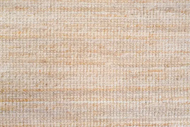 Photo of Beige light peach carpet texture background. Polypropylene carpet, close-up, top view, texture, braided rough pad beige